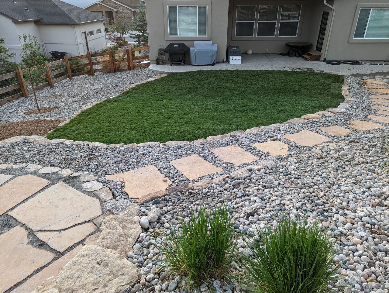 A stone walkway leads to a lush green lawn in front of a house
