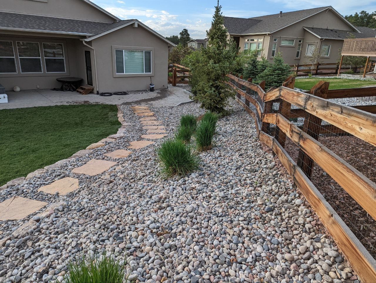 A wooden fence surrounds a gravel path leading to a house