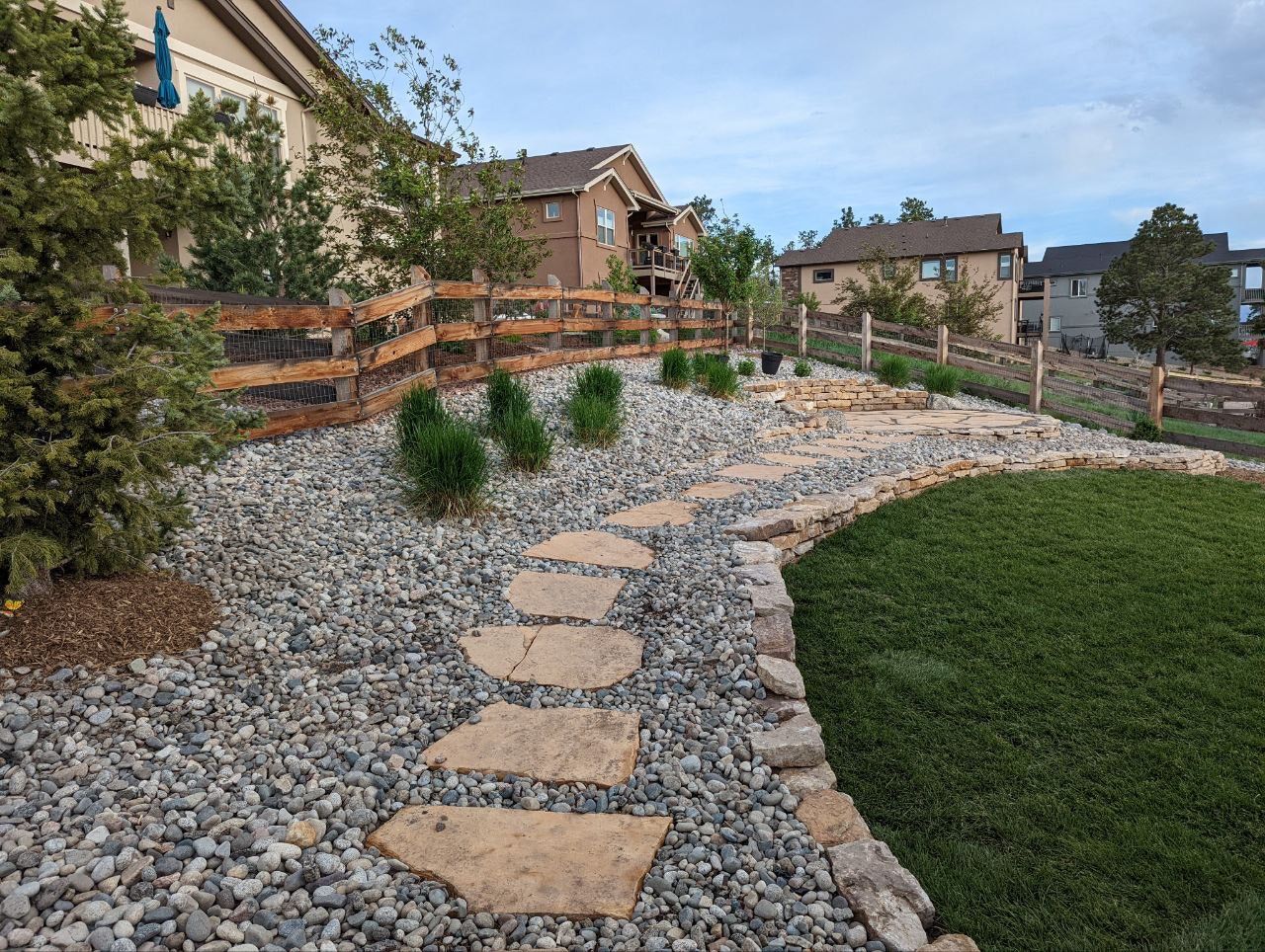 A stone walkway leading to a house with a wooden fence
