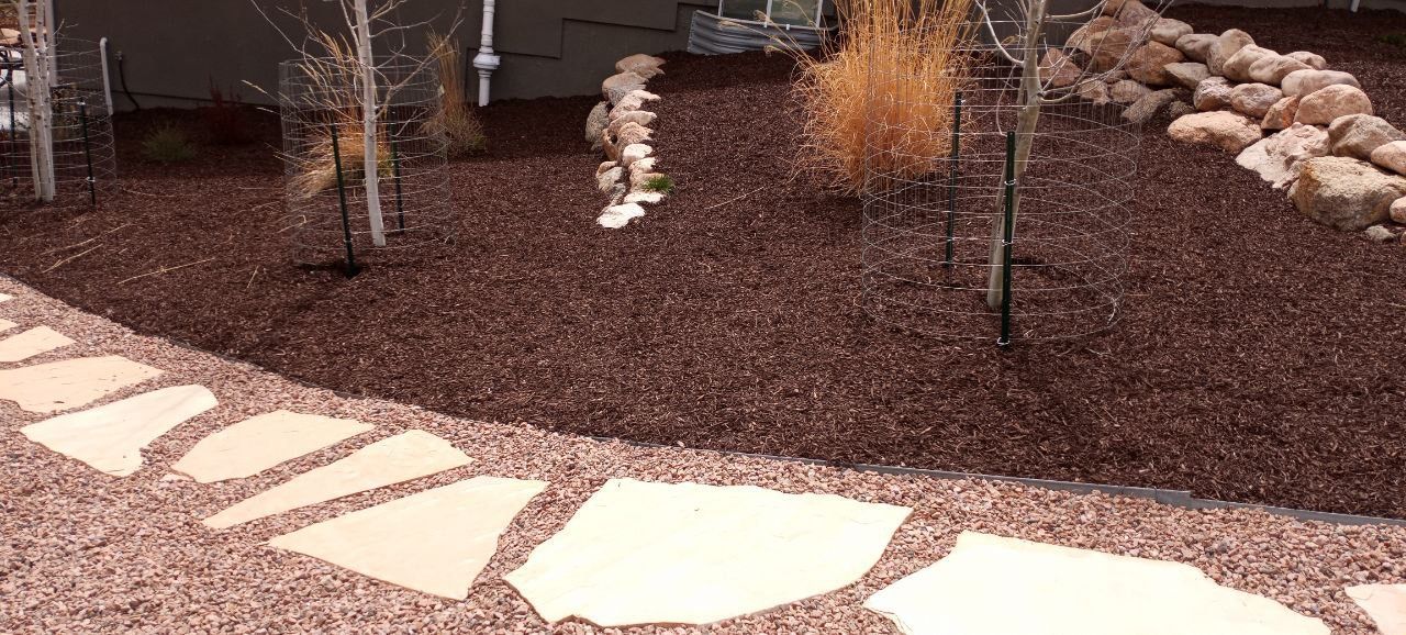 A stone walkway leading to a garden filled with rocks and mulch.