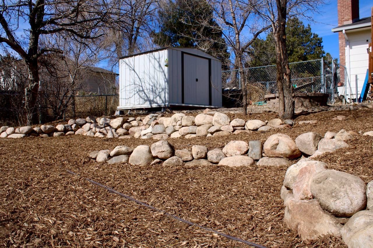 A white shed sits on top of a pile of rocks