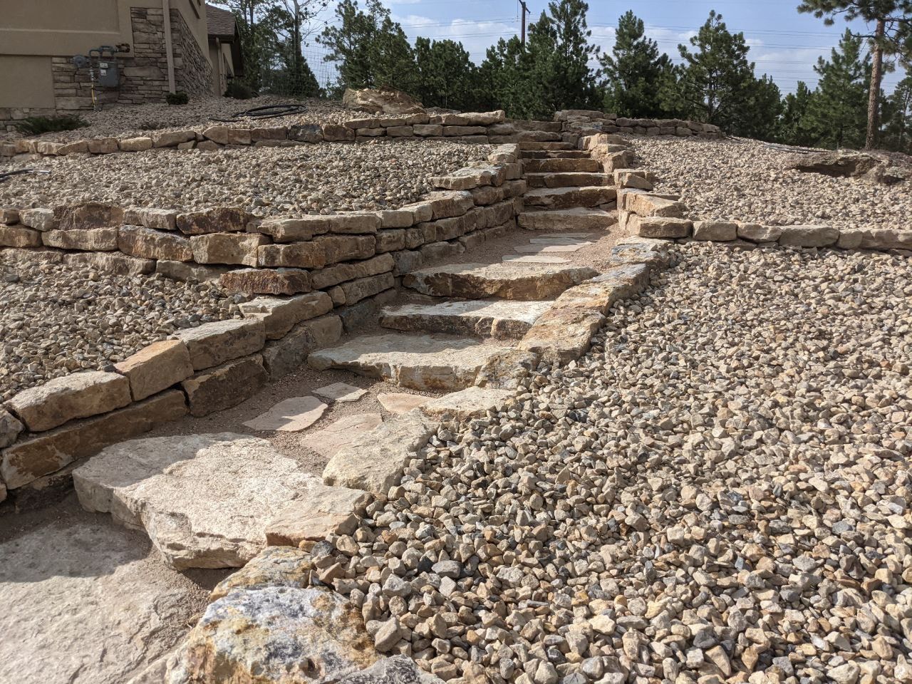 A stone walkway leading up to a house surrounded by gravel and rocks.