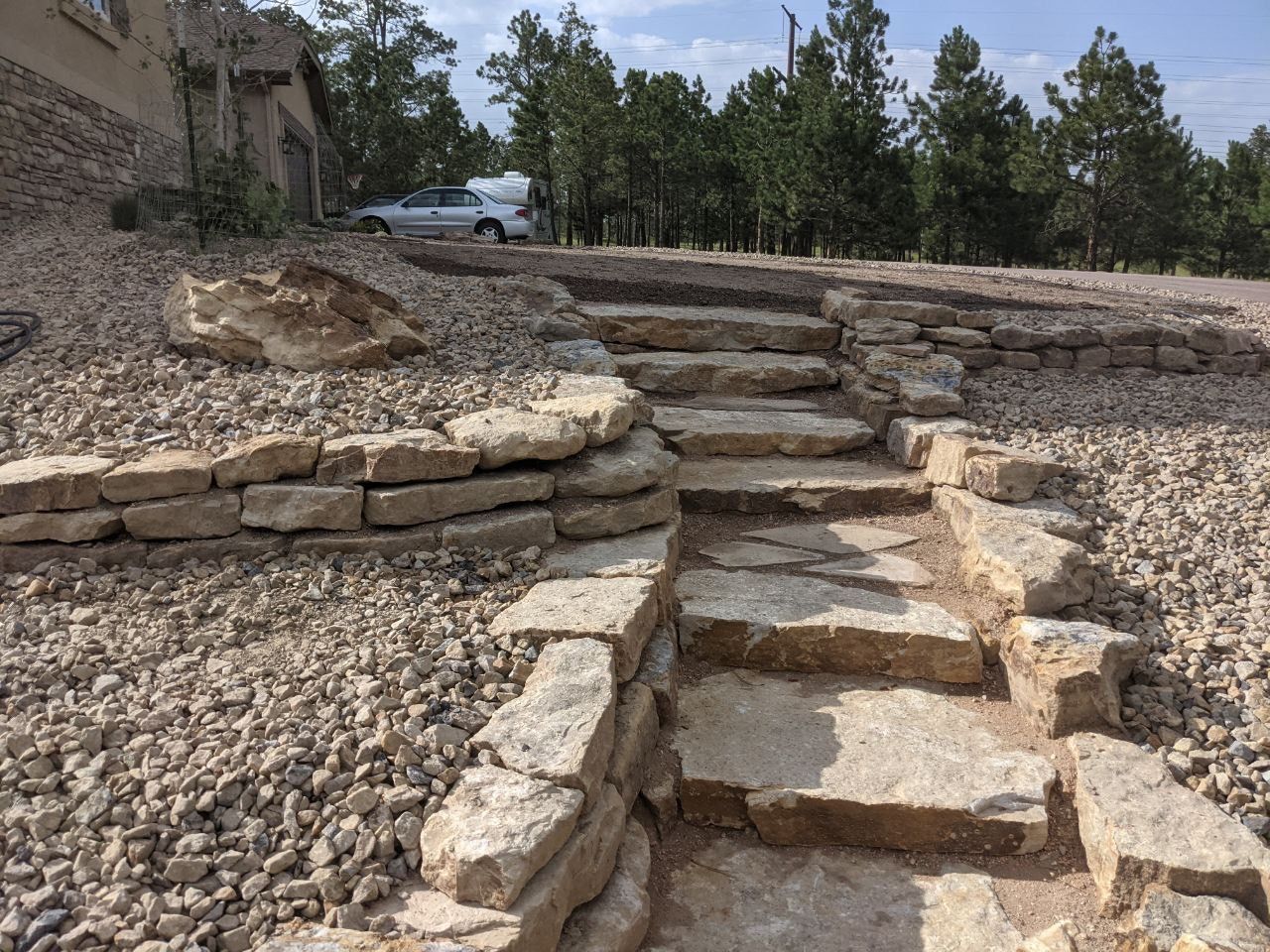 A car is parked on the side of the road next to a set of stone stairs