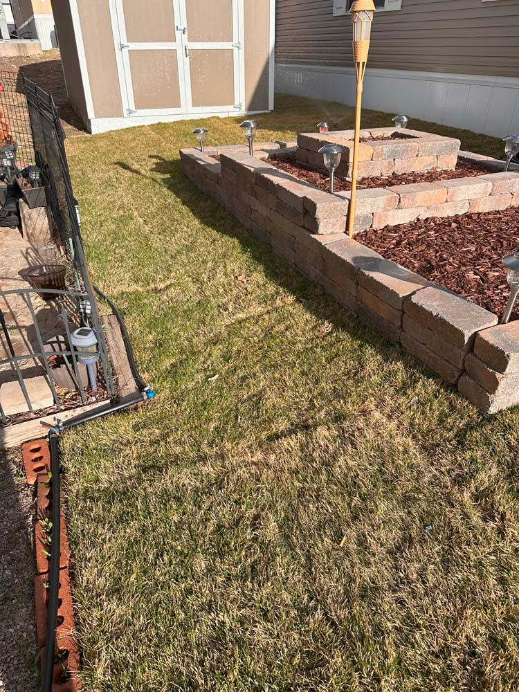 Lawn with brick retaining wall, small shed, and solar lights.