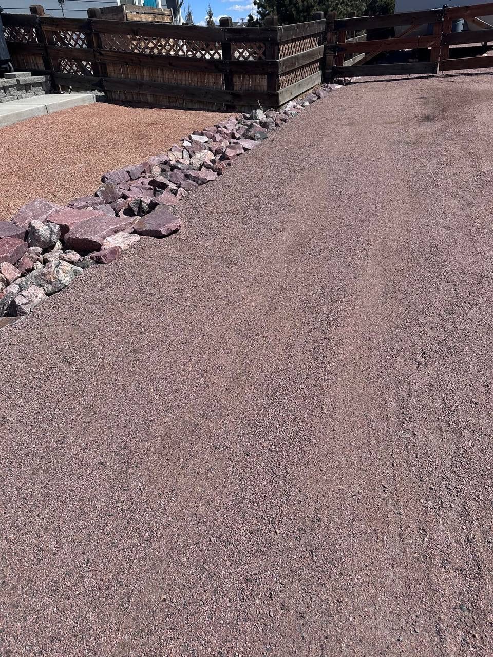 A gravel path with a wooden fence in the background.