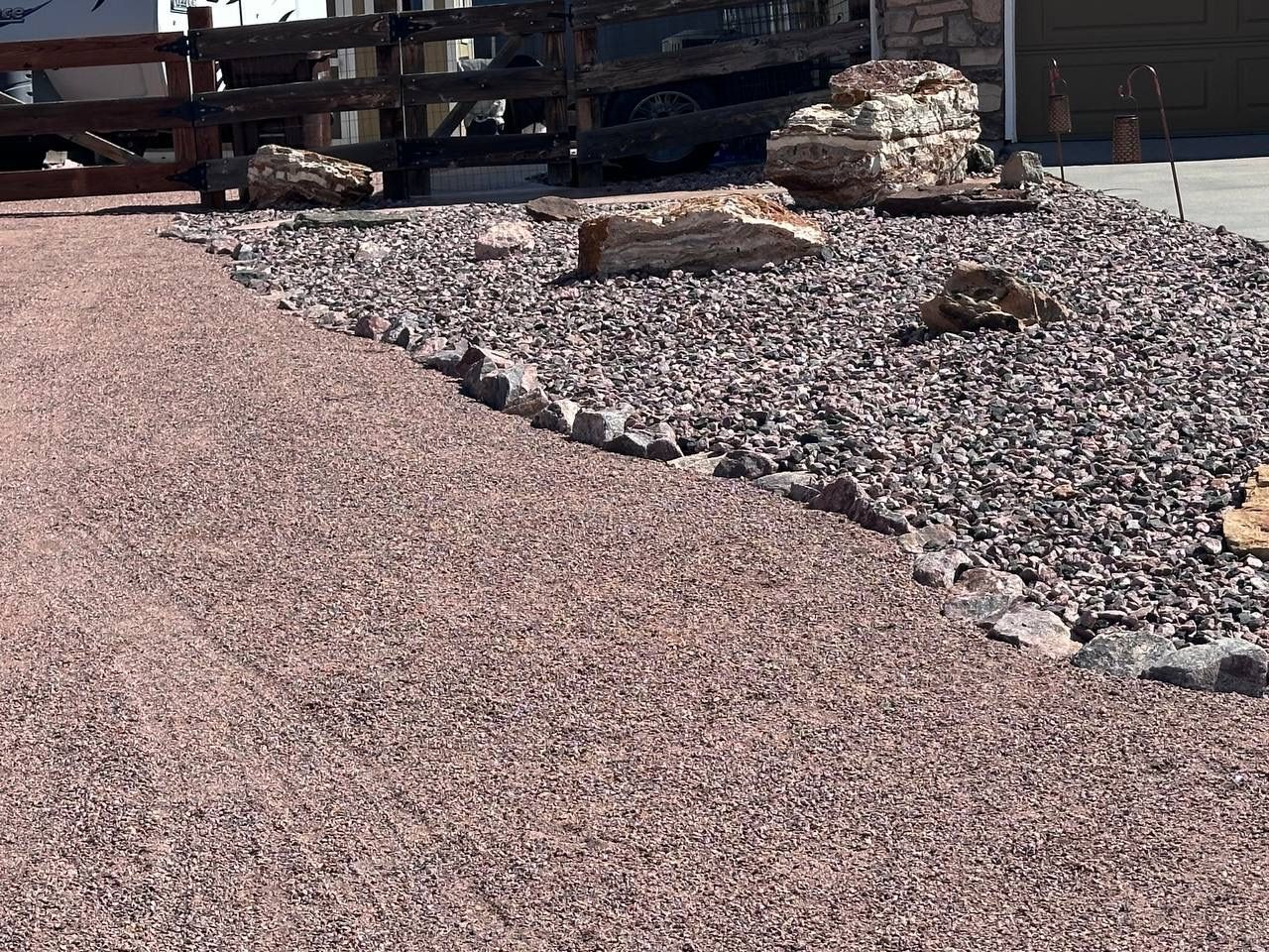A pile of gravel is sitting next to a wooden fence.