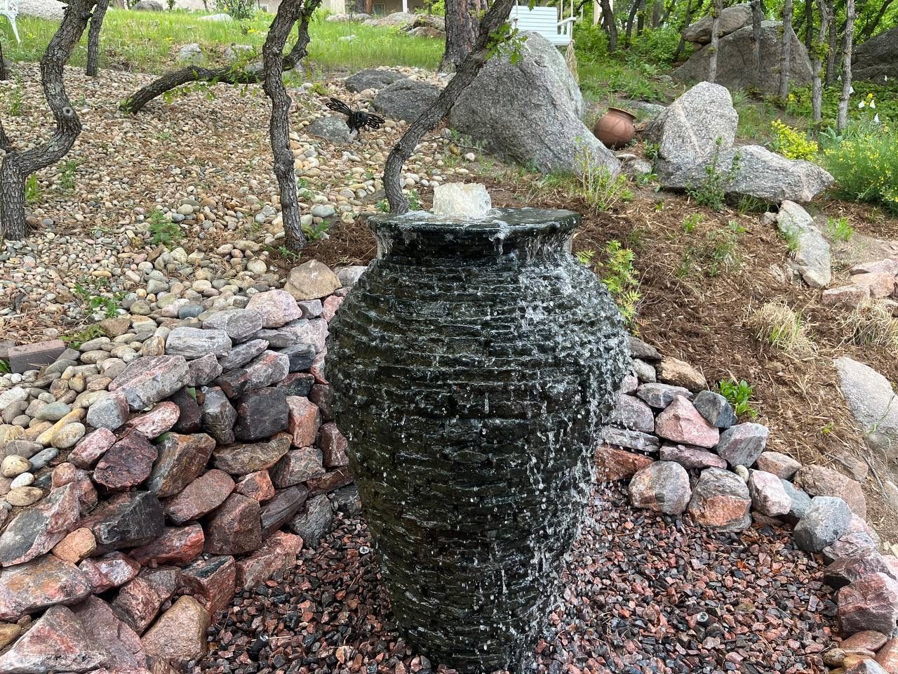 A water fountain is surrounded by rocks in a garden.