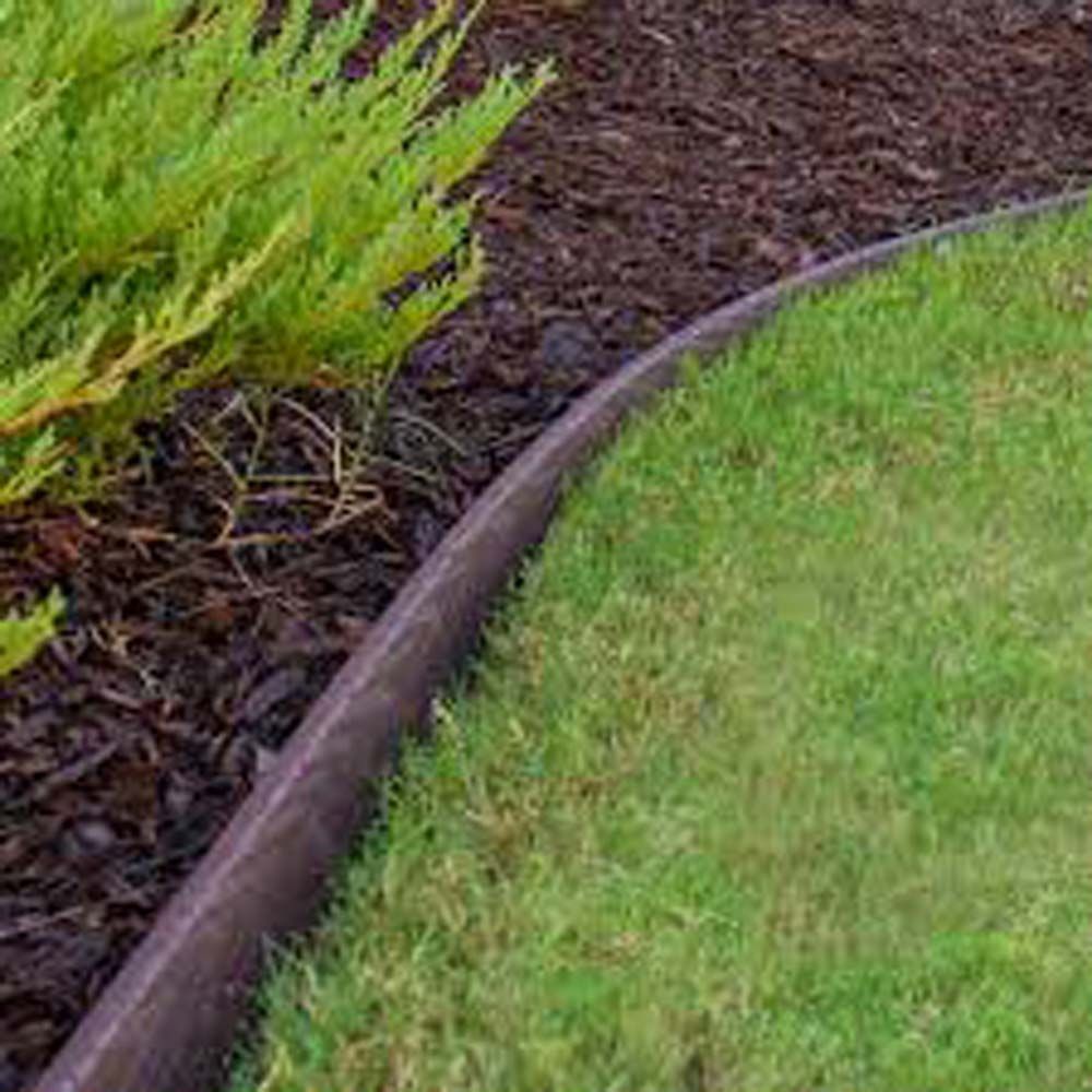 Black plastic edging separates green grass from dark mulch and a green shrub.