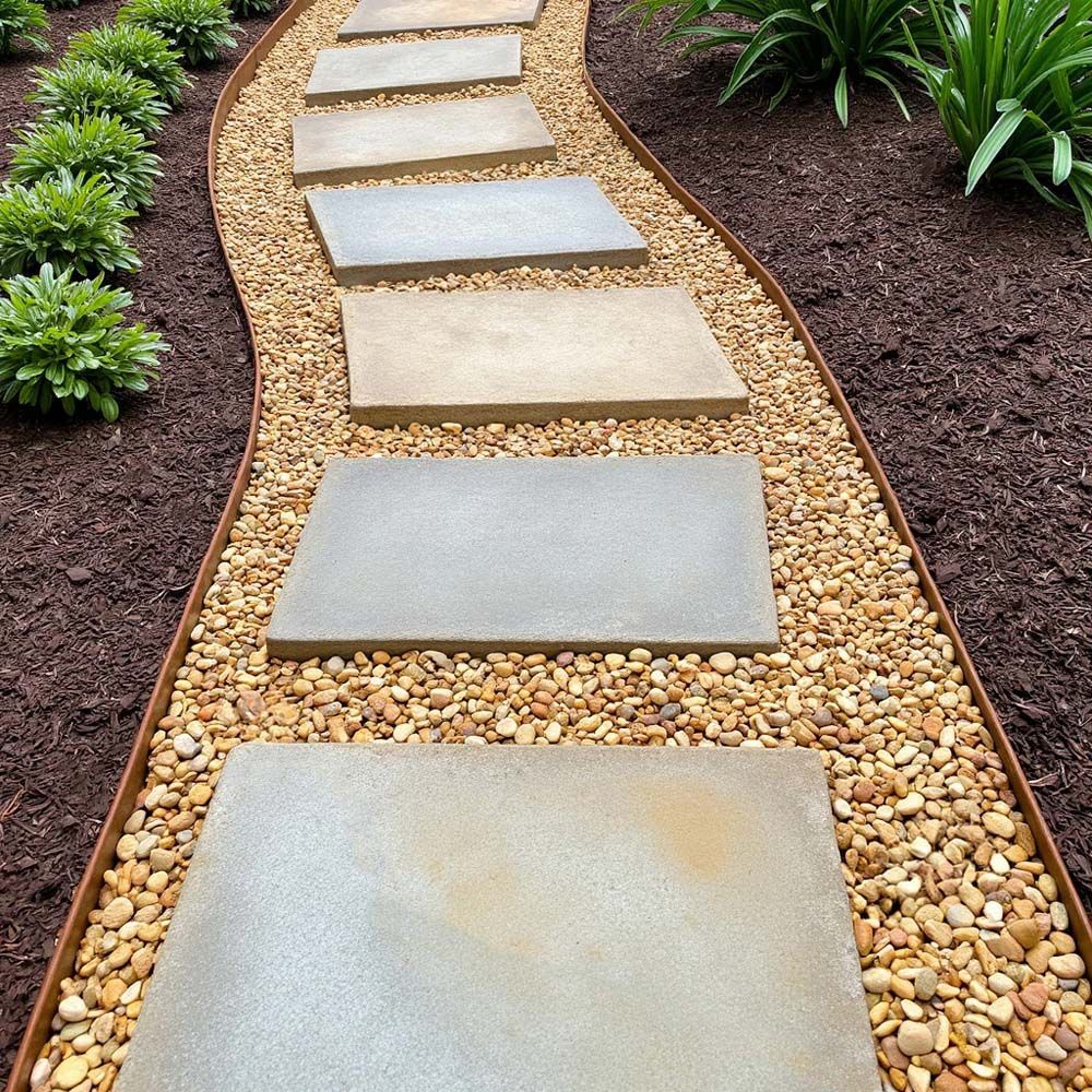 Stepping stone path in garden lined with pebbles, edged by metal.