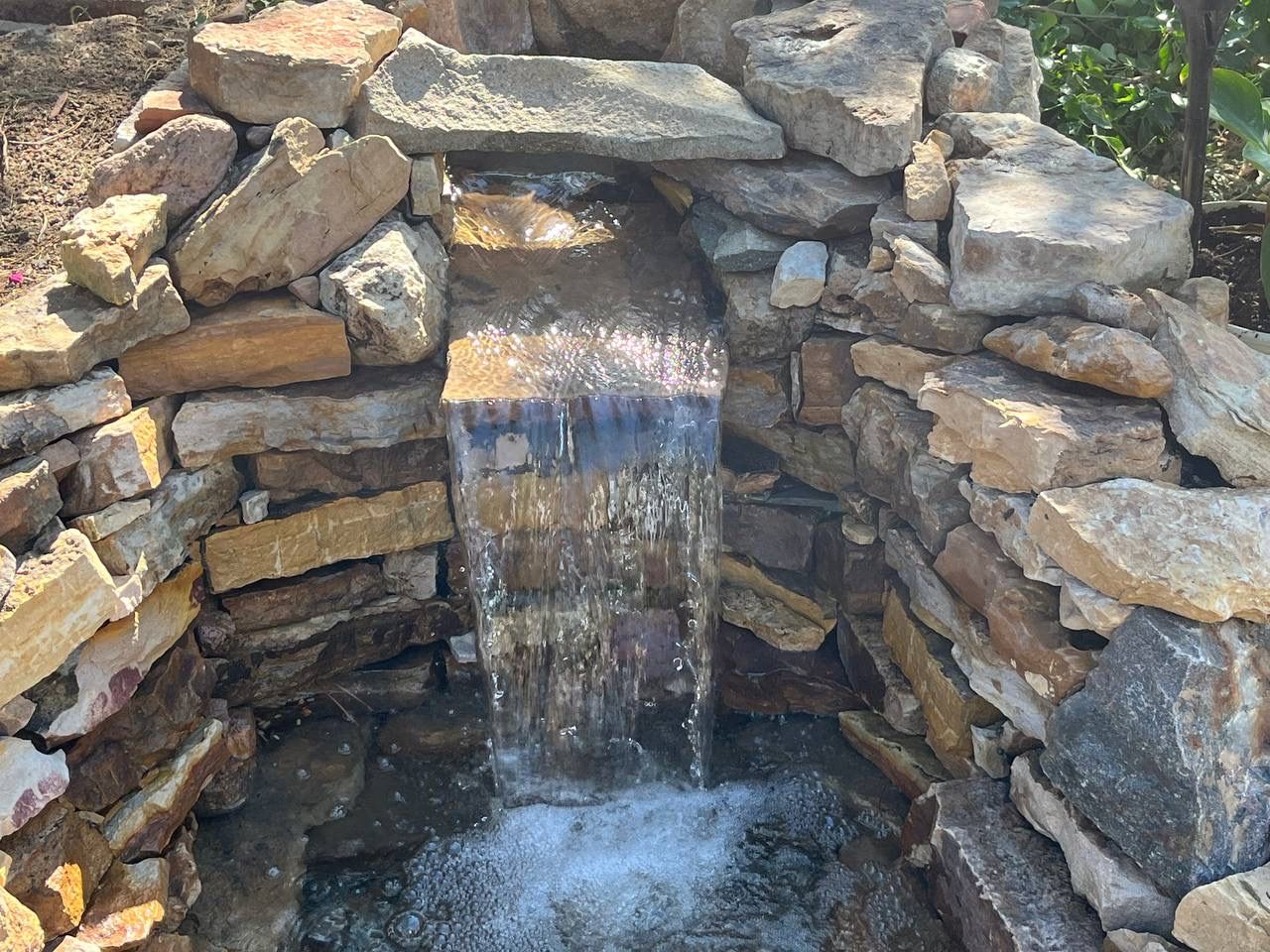 A small waterfall is surrounded by a stone wall.
