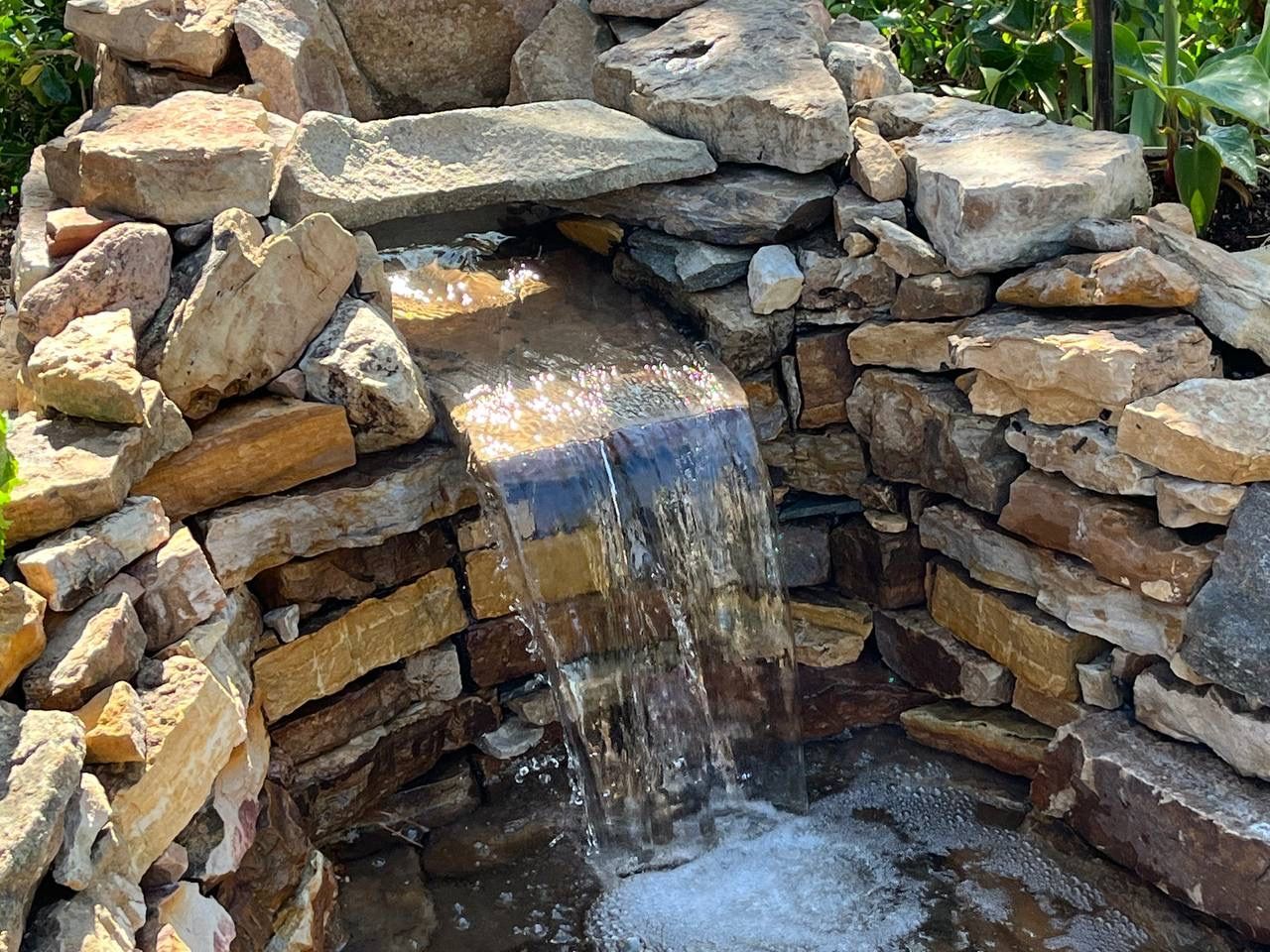 A small waterfall is surrounded by rocks in a garden.