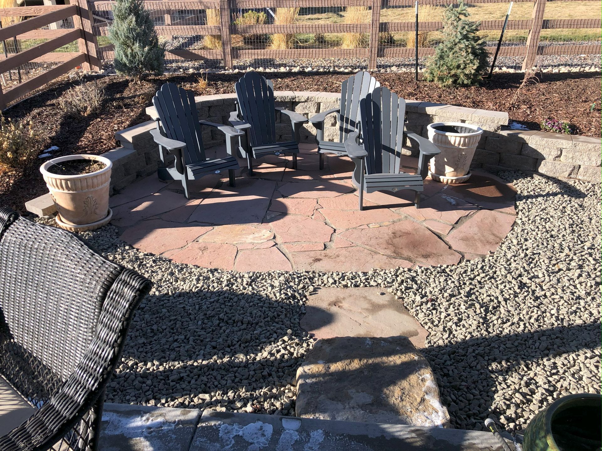 A patio with chairs and a fence in the background