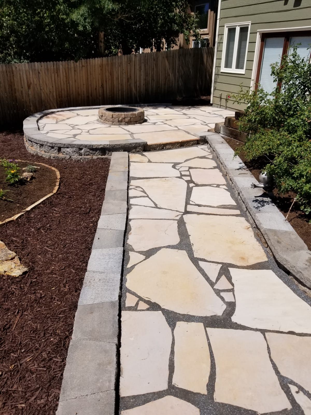 A stone walkway leading to a fire pit in the backyard
