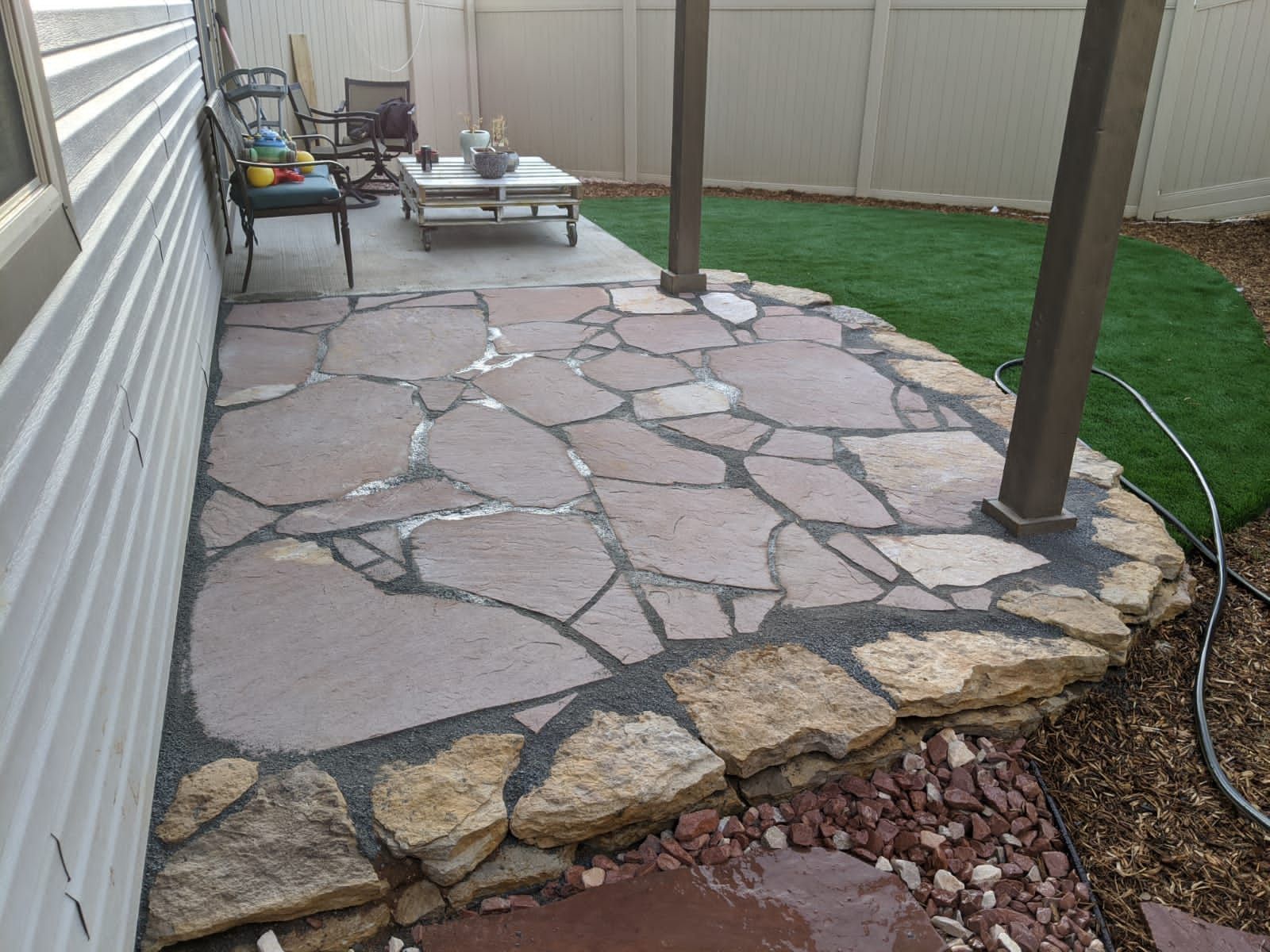 A stone patio with a fence in the background