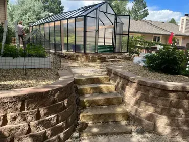 There is a greenhouse in the backyard with stairs leading to it.