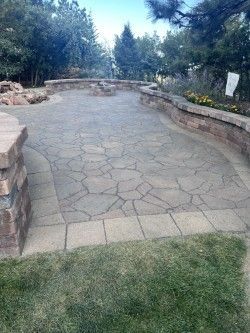A stone patio with a fire pit in the middle of it.