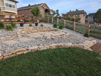 A stone patio with a wooden fence and a house in the background.