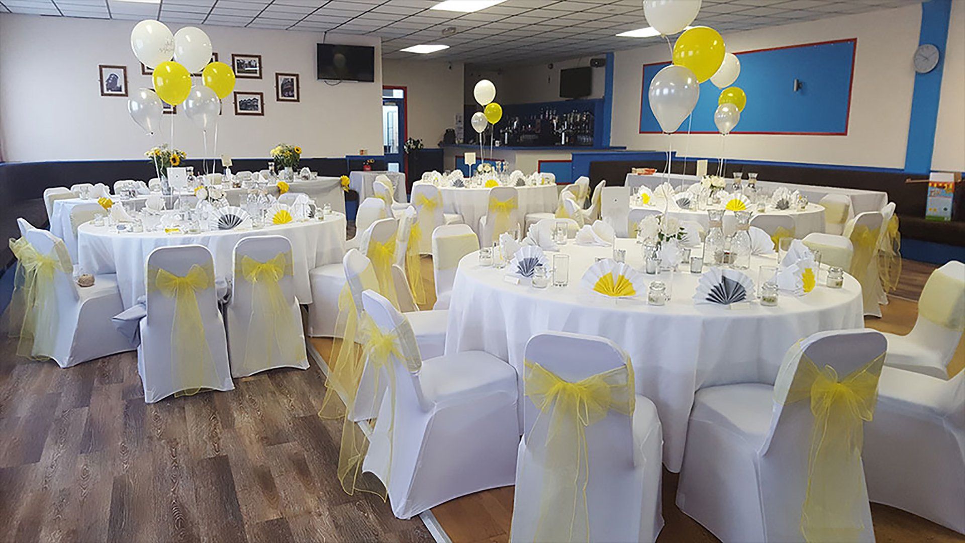 A large room filled with tables and chairs decorated for a wedding reception.