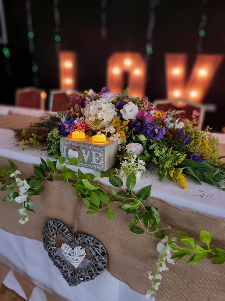 A table with flowers and candles on it and a love sign in the background.