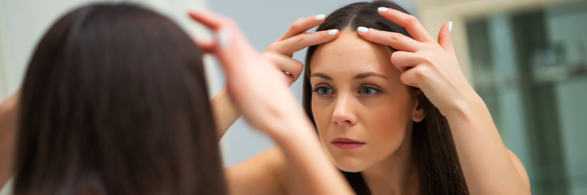 Women looking in the mirror at wrinkles on forehead