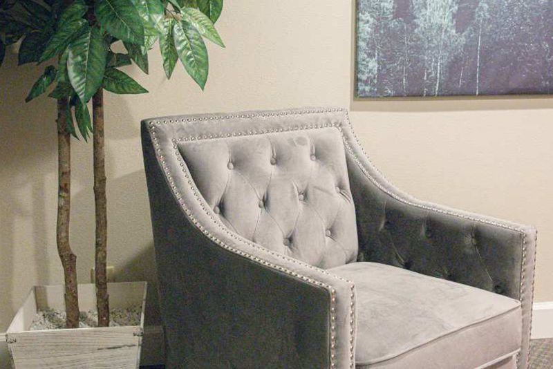 A gray chair is sitting next to a potted plant in a living room.