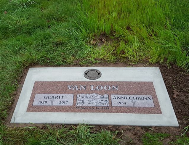 A gravestone for van loon is in the grass.