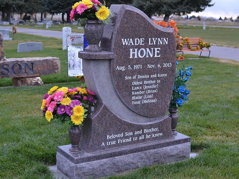 A gravestone for wade lynn hone in a cemetery with flowers in vases