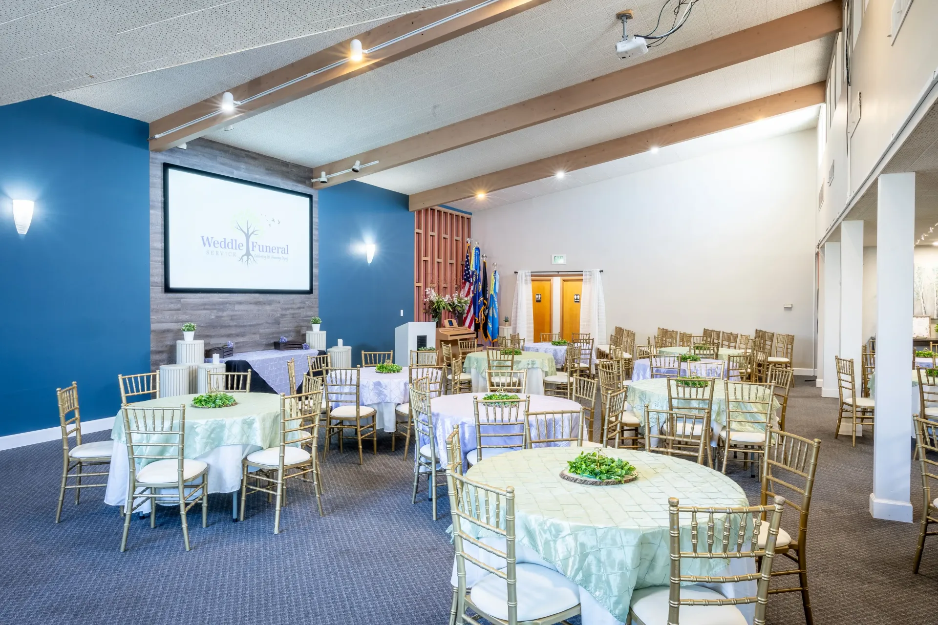 A large room filled with tables and chairs and a large screen.