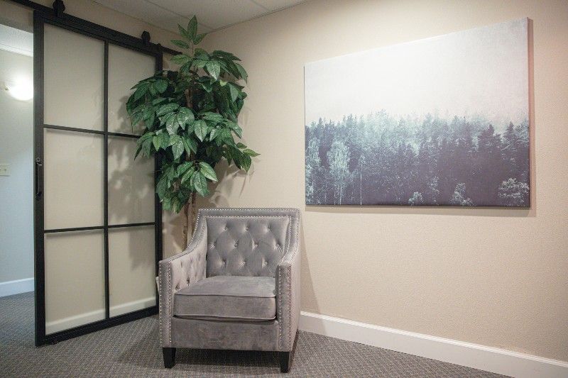 There is a chair and a painting on the wall in the room.