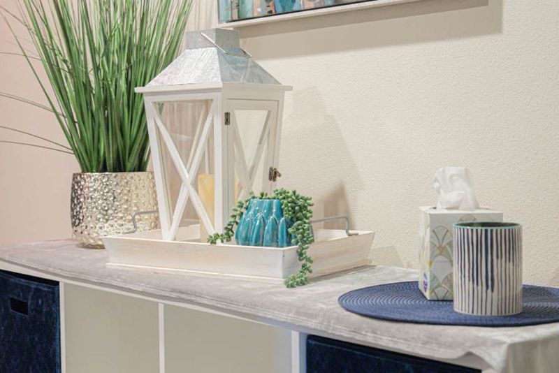 A table with a lantern , vases , tissues and a plant on it.