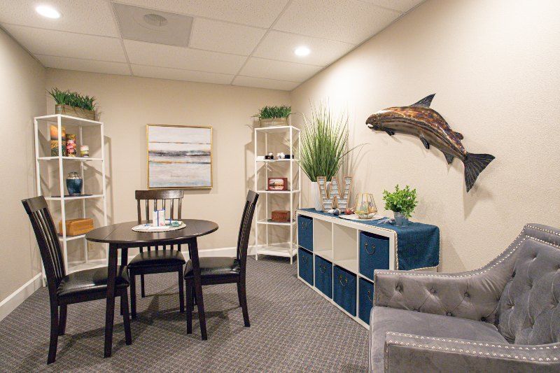 A room with a table and chairs and a fish on the wall.