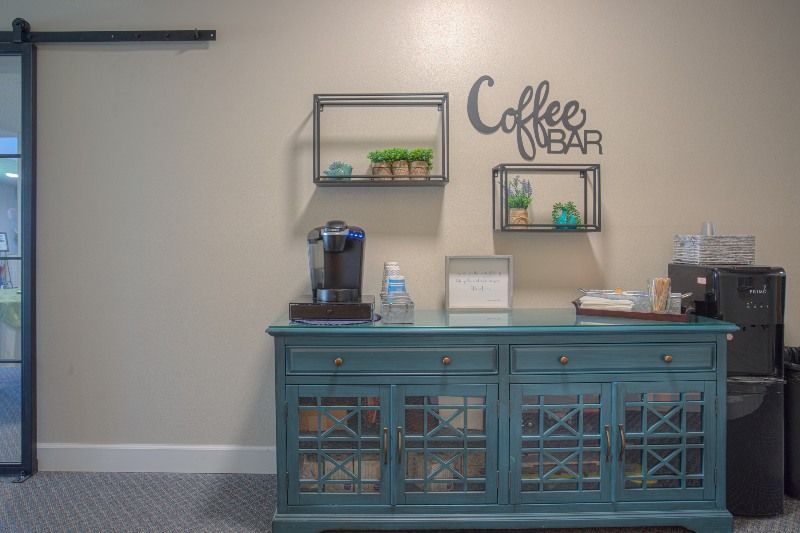 A coffee bar with a coffee maker and a sign on the wall.