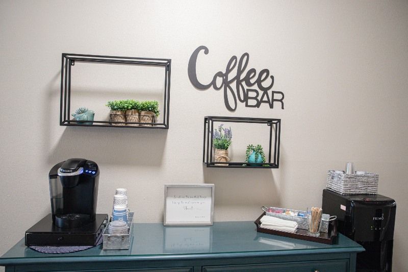 A coffee bar with a coffee maker and shelves on the wall.