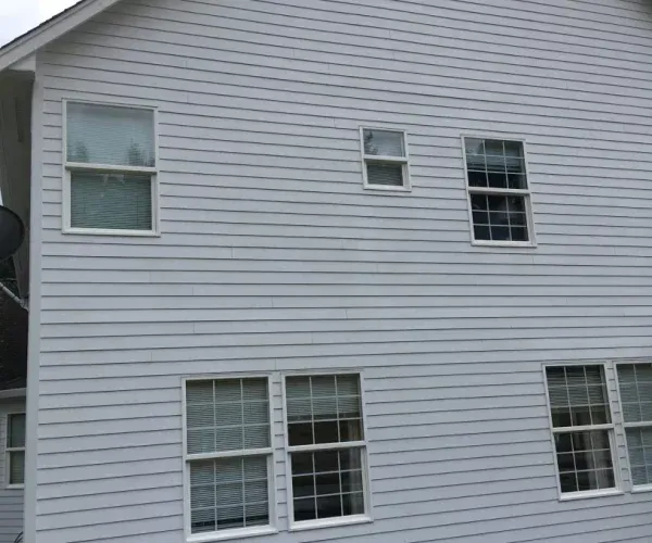Gray house exterior with several white-framed windows on two levels.
