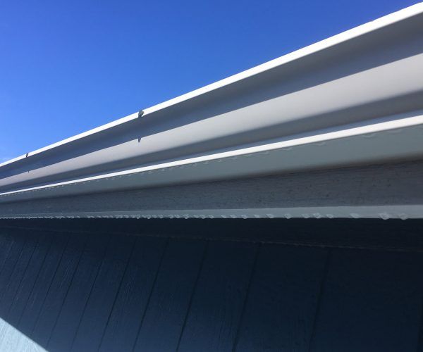Blue sky, white and gray metal roof, a side view with sunlight highlighting the ridges.