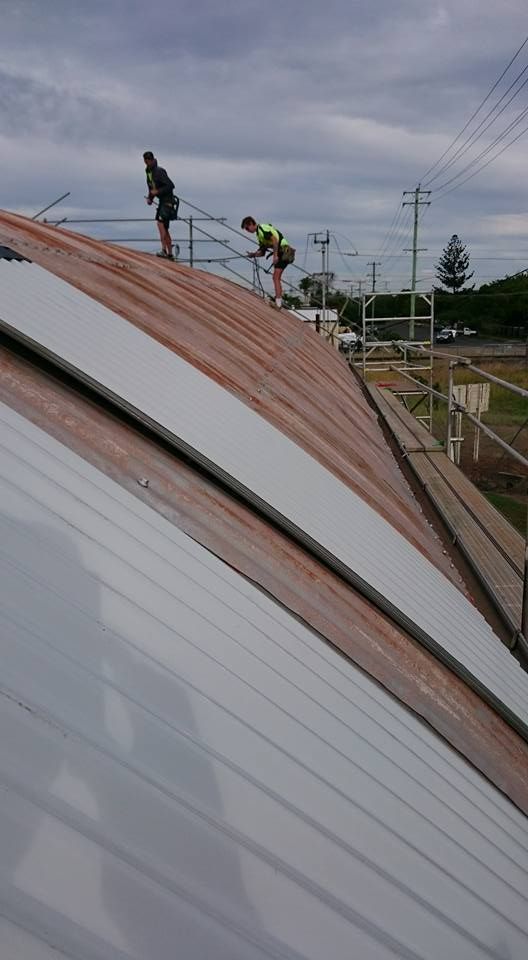 Two Workers on A Curved and Rusted Metal Roof — Kaplan Roofing in Walkervale, QLD