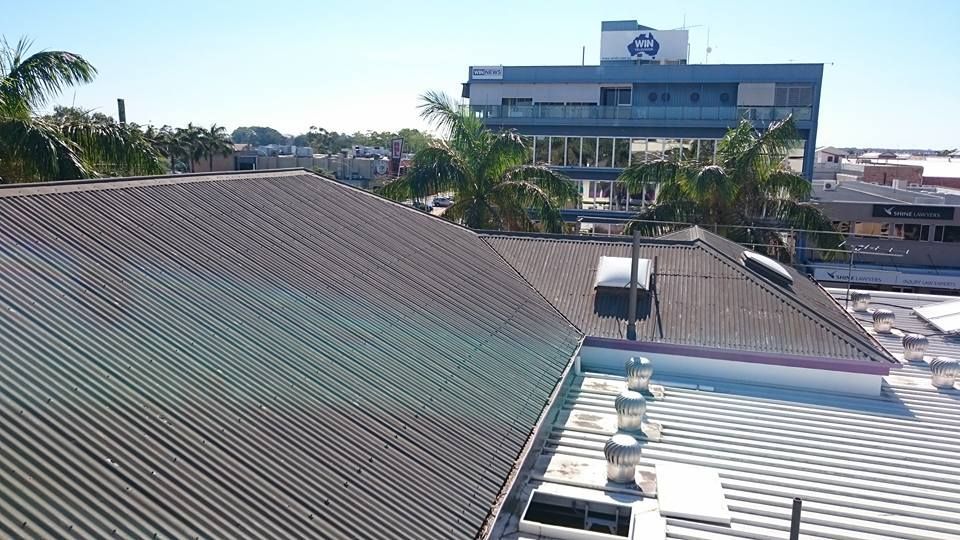 A View of A Corrugated Roof with A Building — Kaplan Roofing in Walkervale, QLD