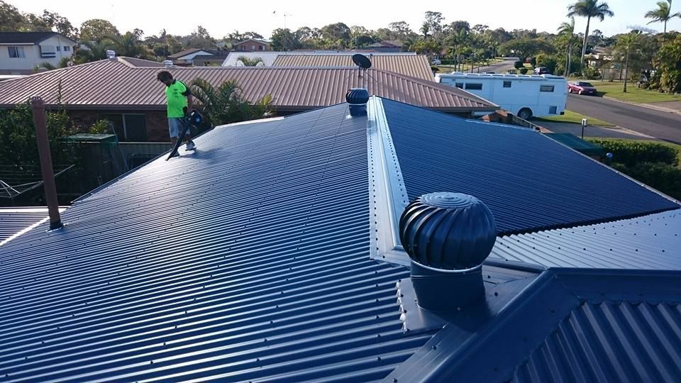 A Person on A Corrugated Metal Roof — Kaplan Roofing in Walkervale, QLD