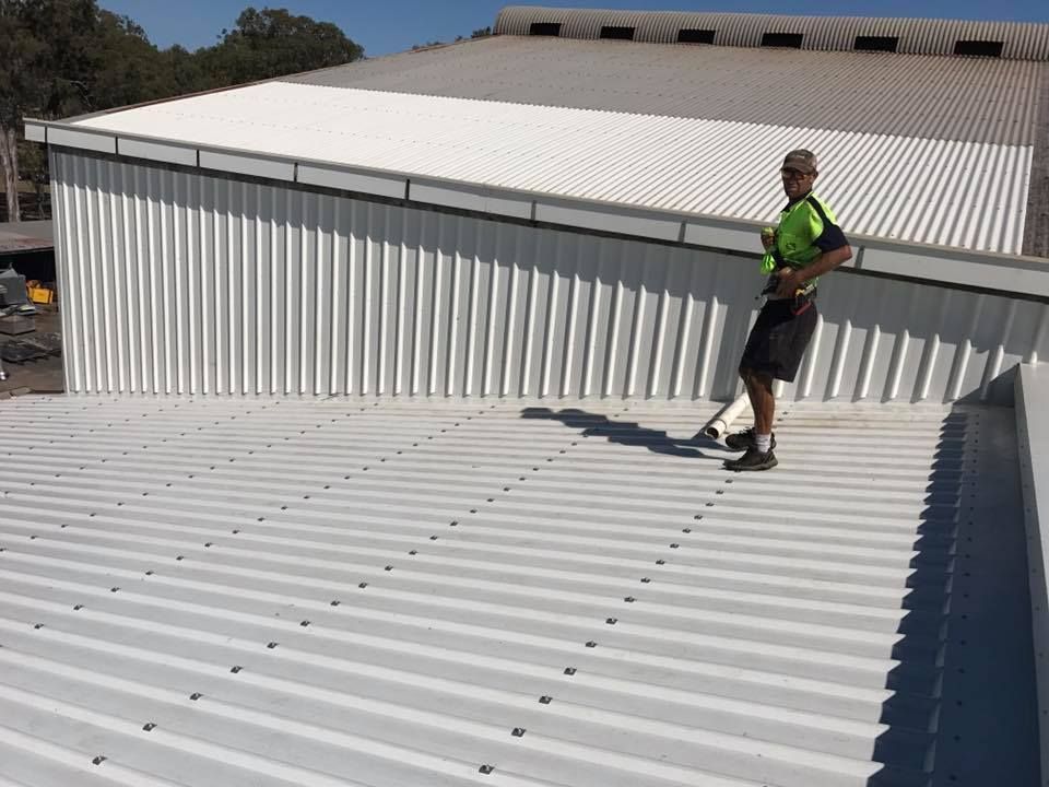 A Man Inspecting the Surface on A Sunny Day — Kaplan Roofing in Walkervale, QLD