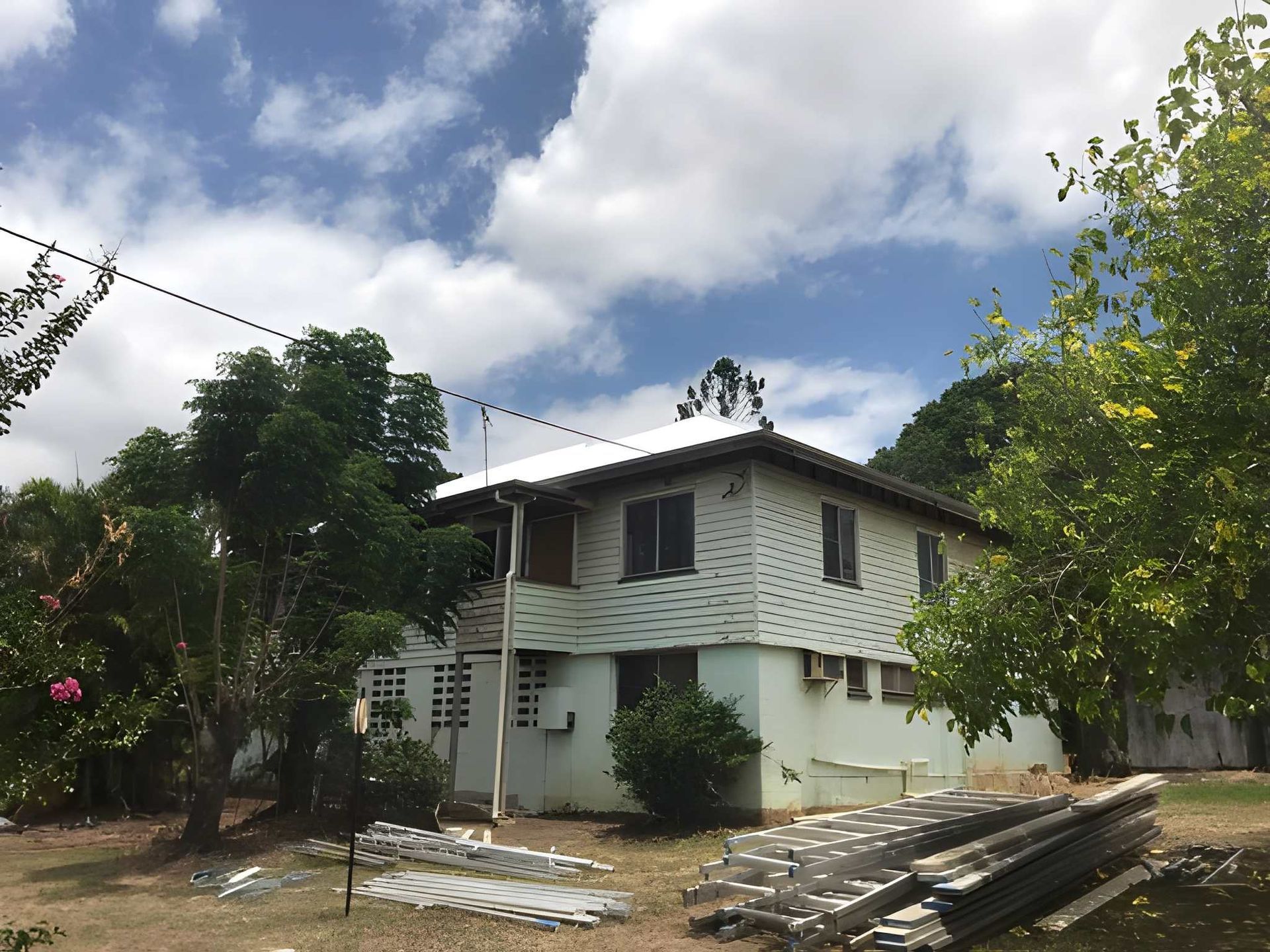A House with Green and White Siding, Surrounded by Trees — Kaplan Roofing in Walkervale, QLD