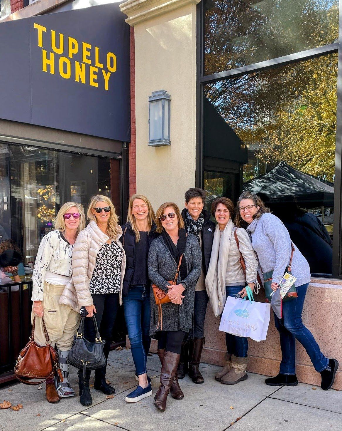 A group of women standing in front of a store called tupelo honey