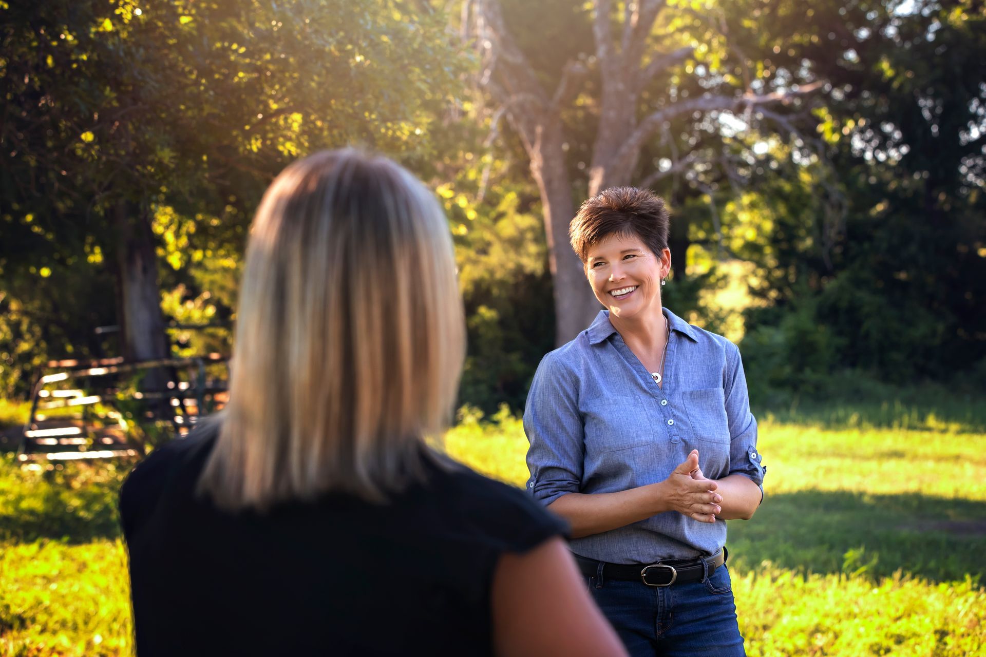 Two women are standing in a field talking to each other.
