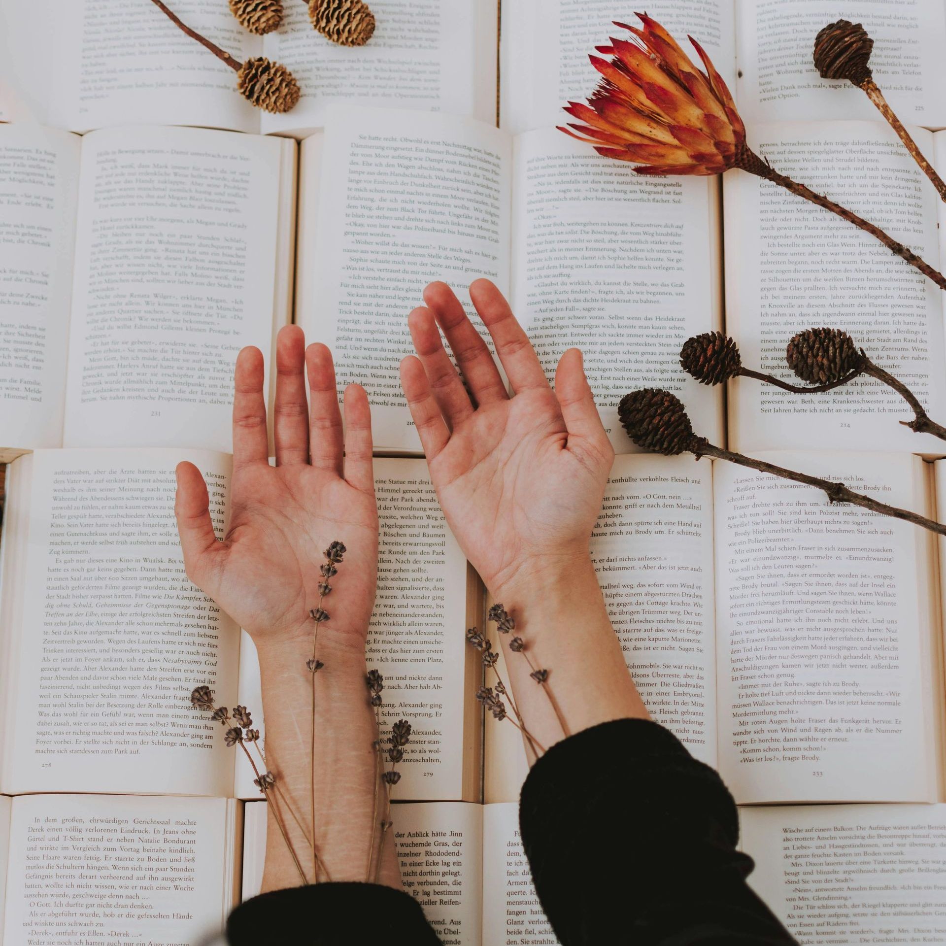 A person laying their hands on a pile of books