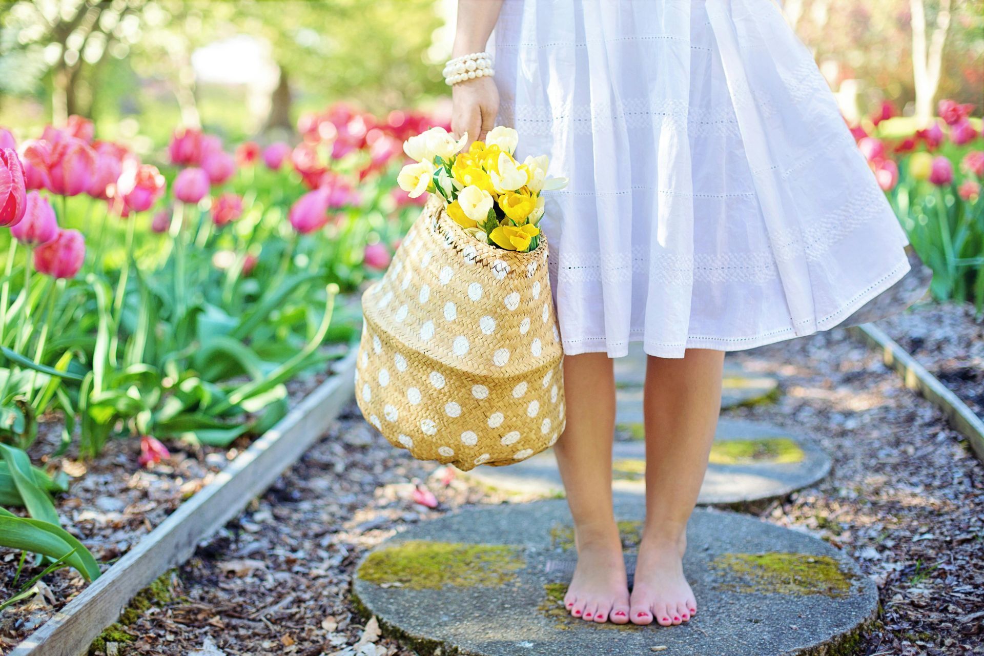 A woman in a white dress is holding a basket of flowers.