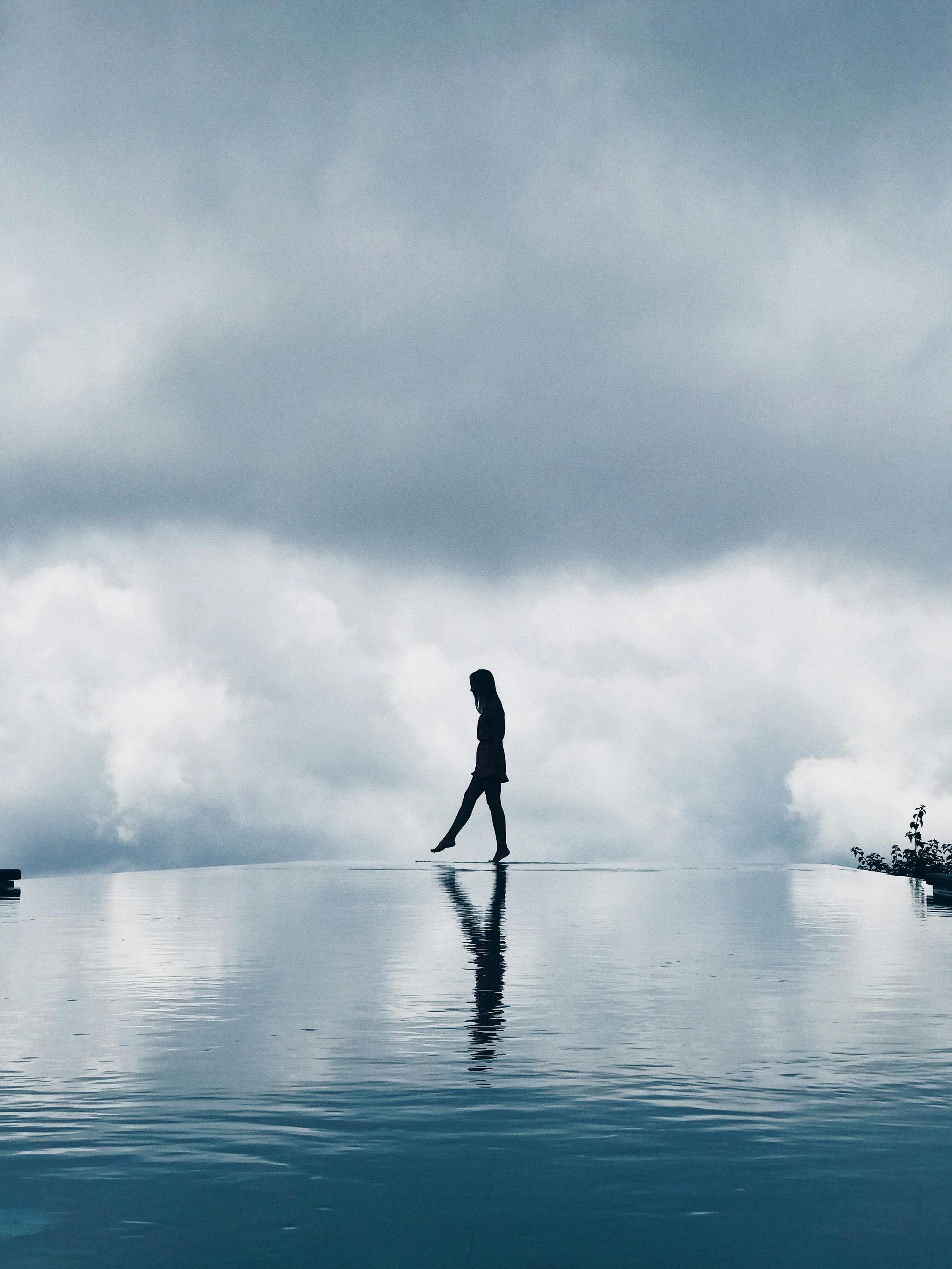 A silhouette of a person standing on top of a body of water