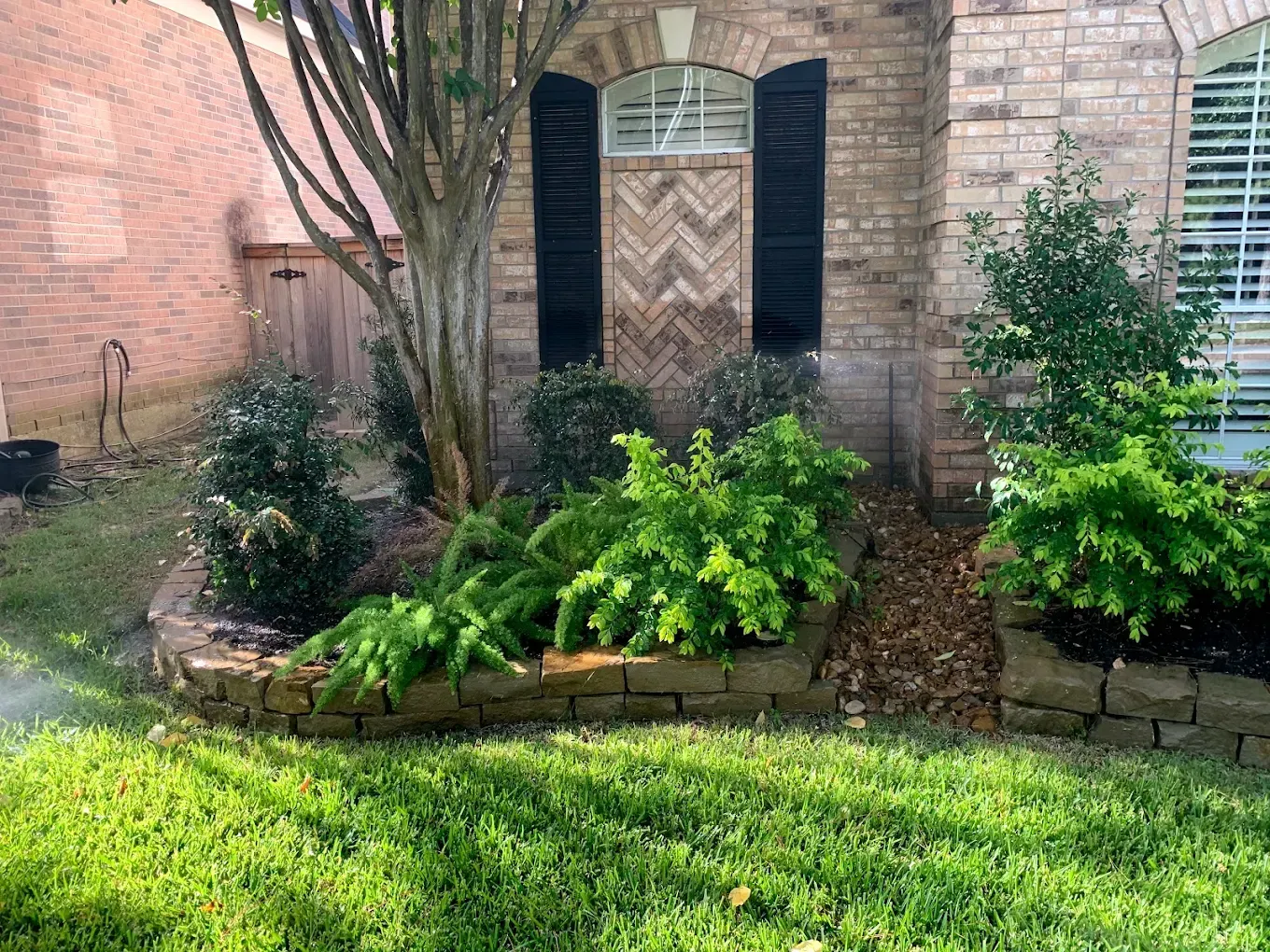 A two-story brick house with a curved walkway, green lawn, and shrubbery.
