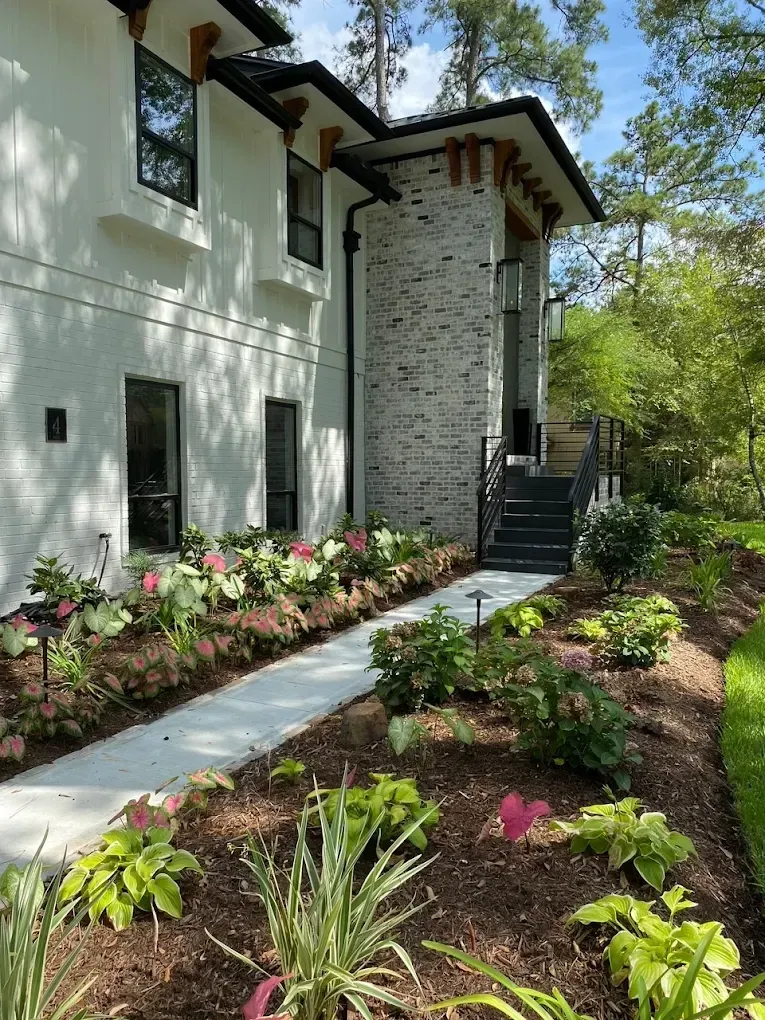 White and grey brick house with a pathway and landscaped garden.