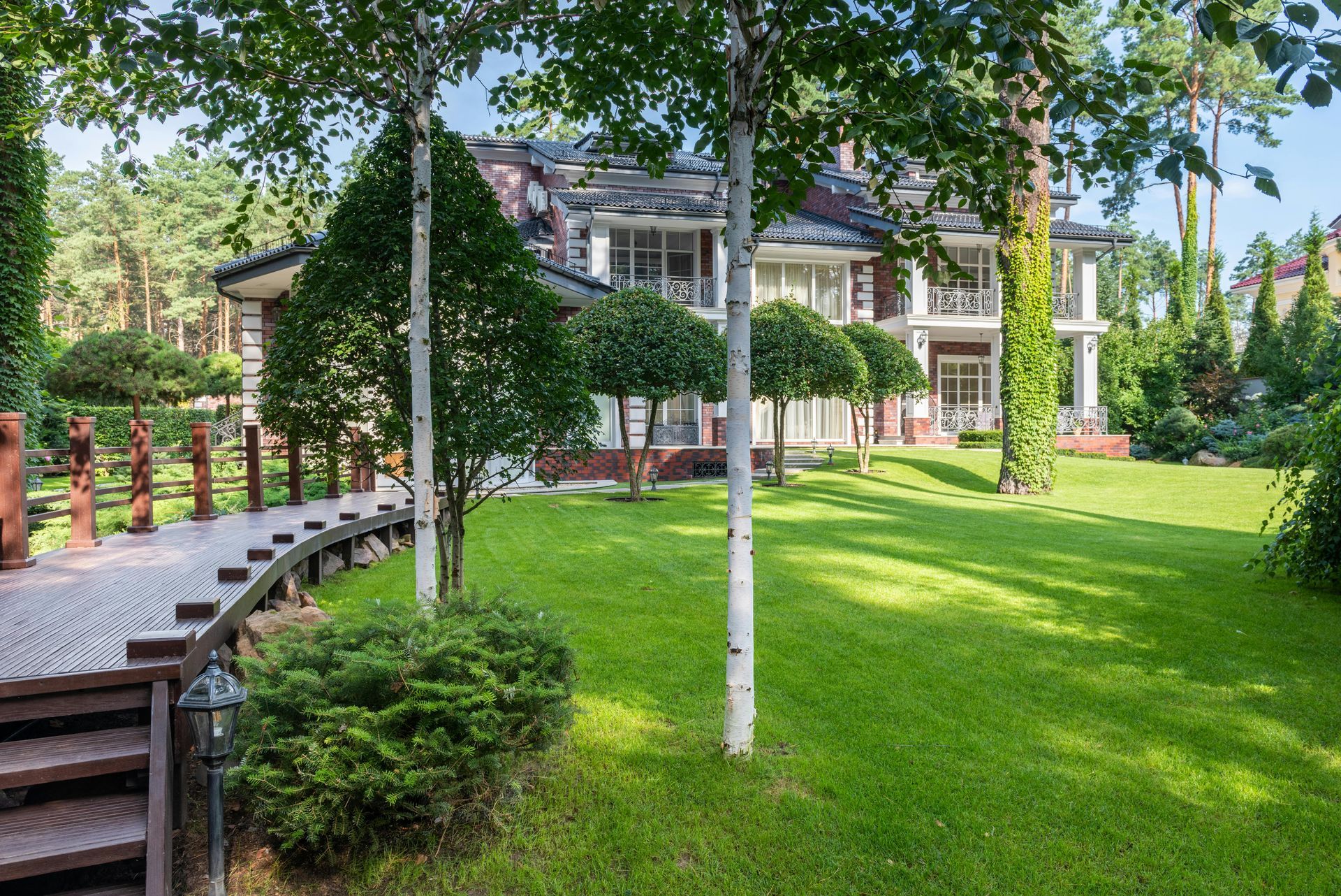 A two-story brick house with a curved walkway, green lawn, and shrubbery.