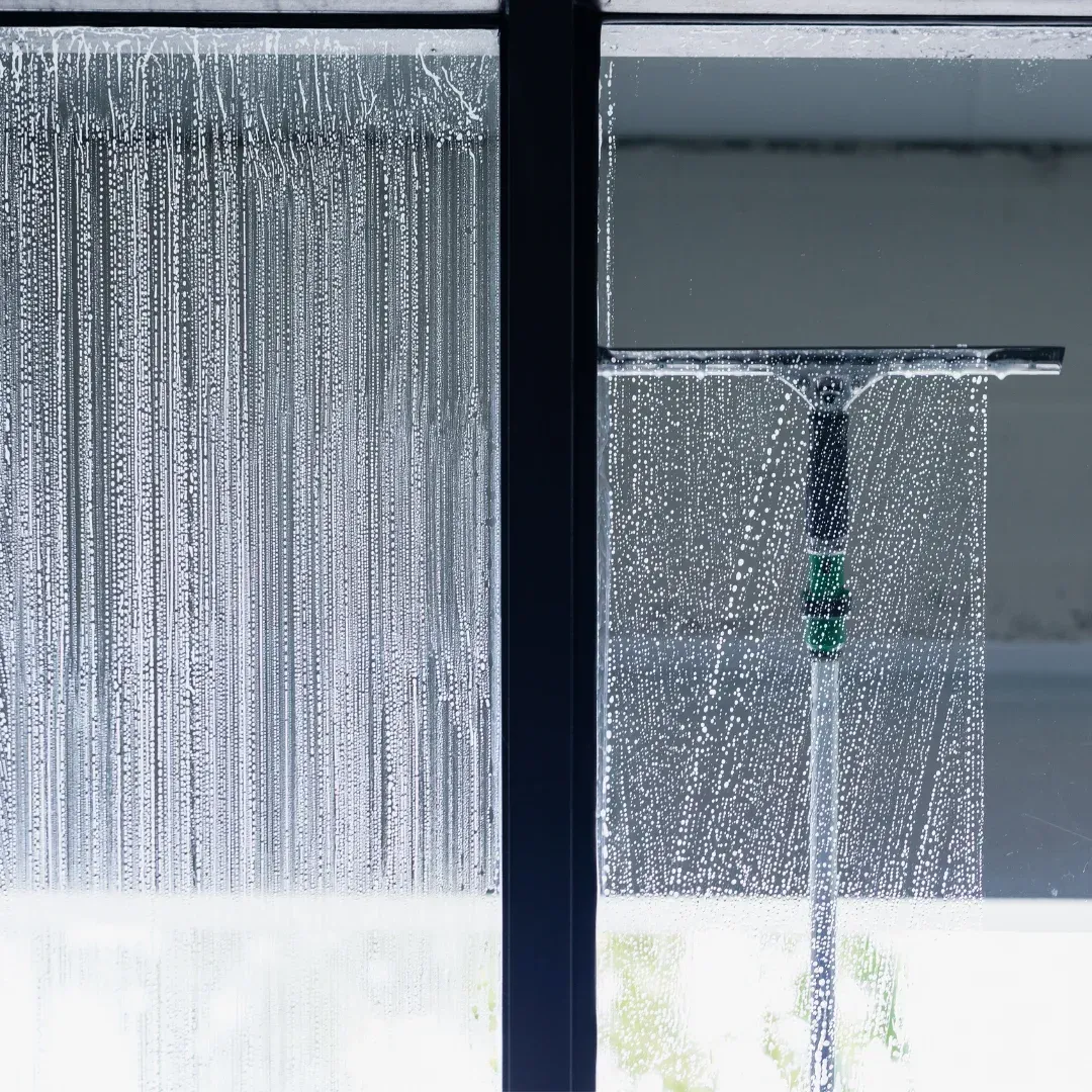A close up of a window being cleaned with a hose.