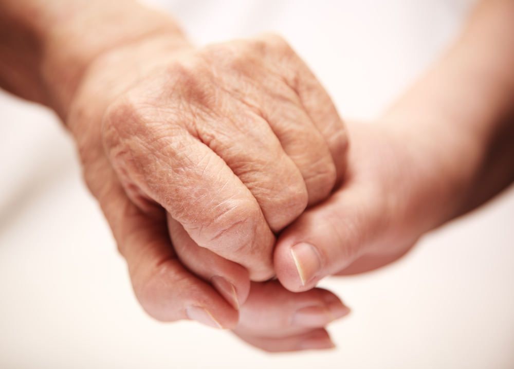 a young woman is holding an older woman 's hand .